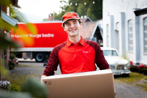 Smilende yrkessjåfør fra Posten holder en pakke