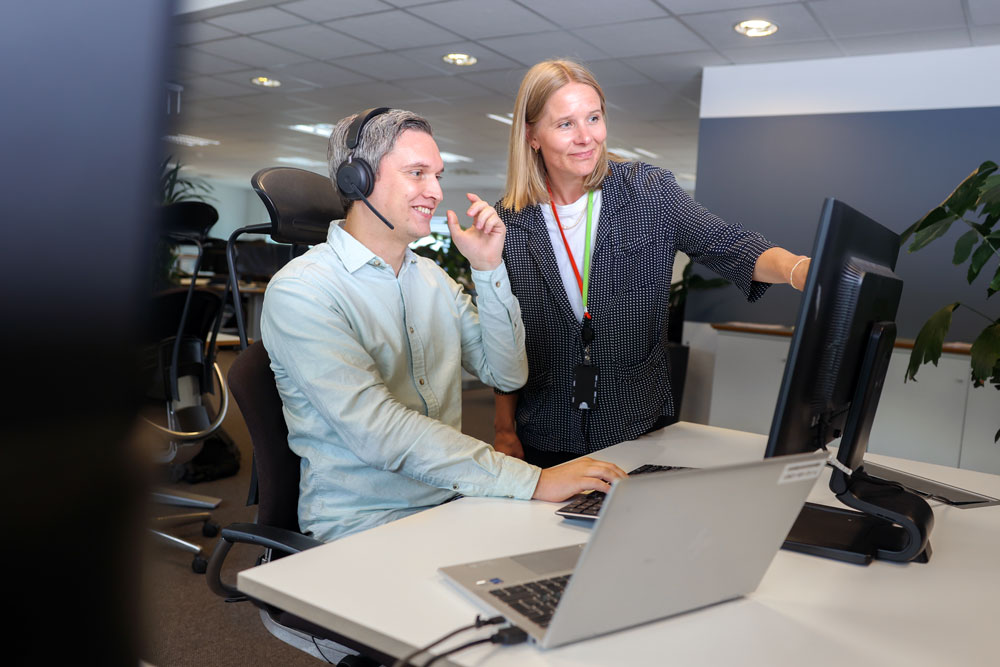 To ansatte i Shared Service Centre (SSC) HR og Lønn ser på en skjerm